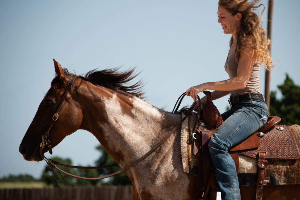 A girl rides her Thoroughbred with a unique white marking on her shoulder
