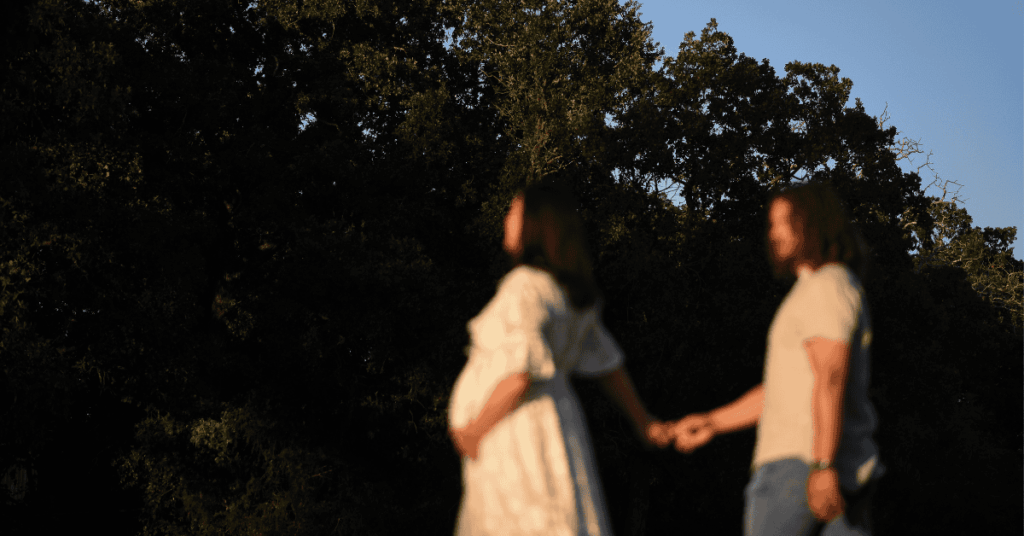 Candid maternity photo of a first-time mom with her husband, cradling her baby bump with a quiet smile