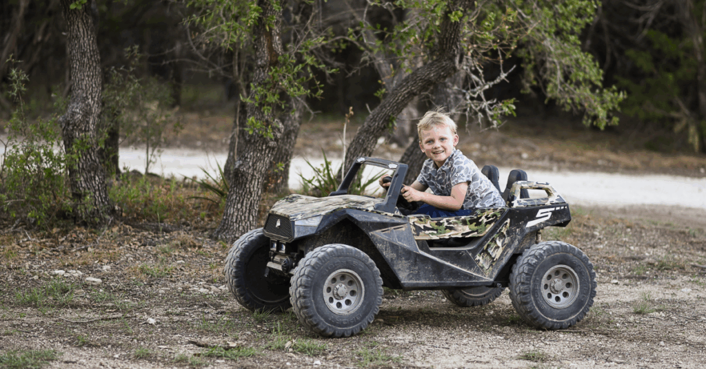 Son zooms by on ATV smiling at the camera in a chaotic family photography scene